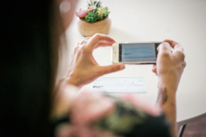 A photo of a person using a mobile device to take a photo of a check for movile deposit using the Legends Bank mobile banking app.