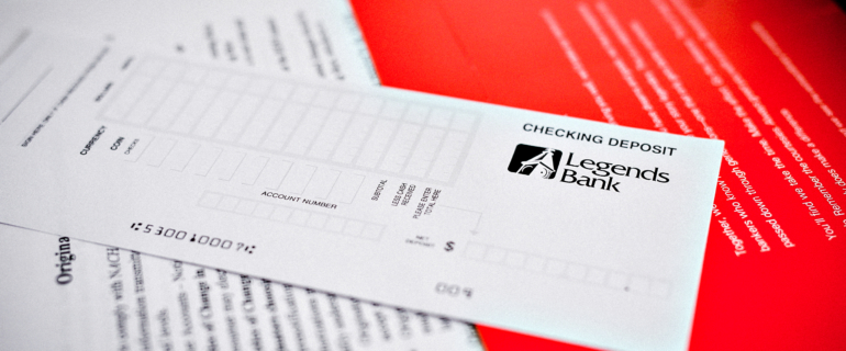 A photo of a close-up of a Legends Bank Checking Deposit slip.