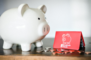 A photo of a piggy bank with coins next to a Legends Bank savings booklet.