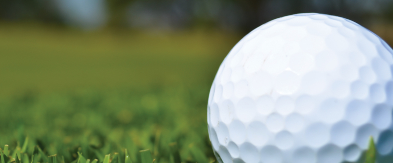 A photo of a close-up of a golf ball in grass.